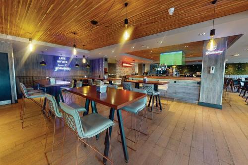 a restaurant with tables and chairs and a bar at Village Hotel Birmingham Dudley in Dudley