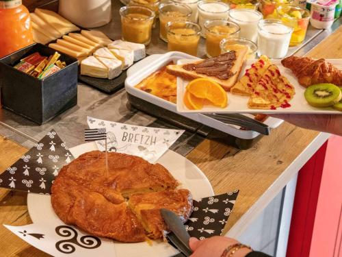 a table topped with a plate of bread and food at ibis Pontorson Baie Du Mont Saint Michel in Saint-Georges-de-Gréhaigne