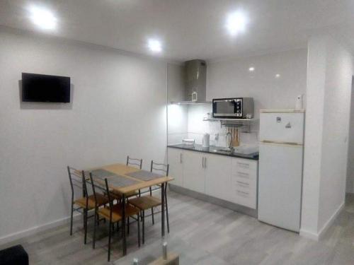 a kitchen with a table and chairs and a refrigerator at Villa - Sleeps 4 & Free Parking in Ribeira Grande