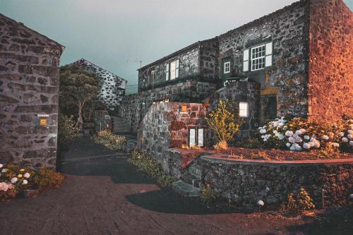 a stone building with flowers in front of it at Adegas do Pico in São Roque do Pico