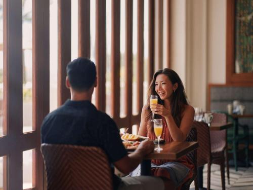 a man and a woman sitting at a table with drinks at Fairmont Kea Lani, Maui in Wailea