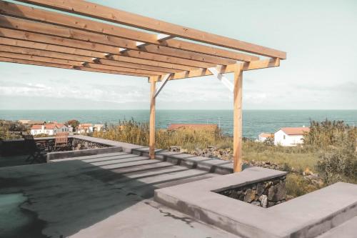 a wooden pergola with a view of the ocean at Adegas do Pico in São Roque do Pico