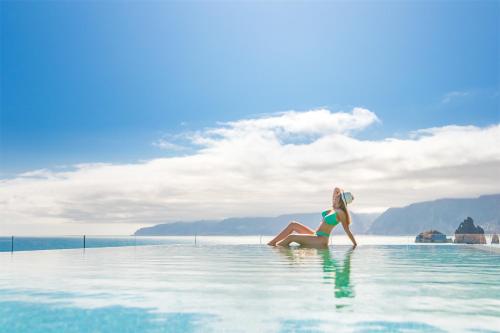 a woman sitting in the water in a infinity pool at Aqua Natura Bay in Porto Moniz
