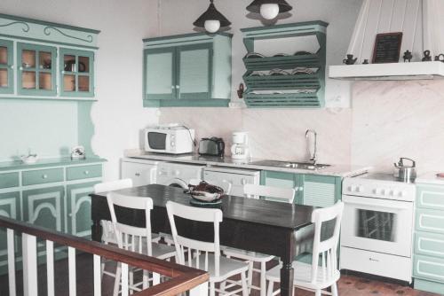 a kitchen with green cabinets and a table and chairs at Adegas do Pico in São Roque do Pico