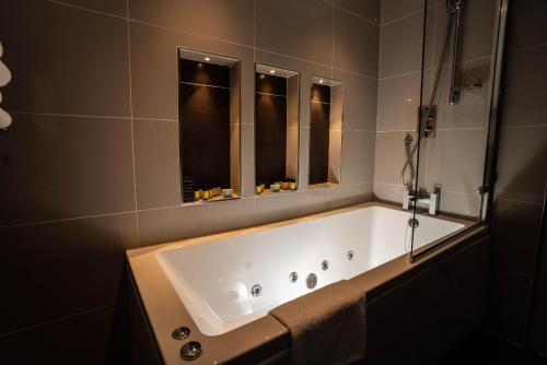 a bath tub in a bathroom with two windows at Killaloe Hotel & Spa in Killaloe