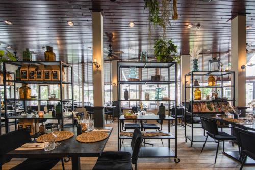 a restaurant with tables and shelves with plants at Buitenplaats de Bergse Bossen in Driebergen