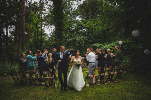 una sposa e uno sposo che camminano lungo la navata al loro matrimonio di Buitenplaats de Bergse Bossen a Driebergen