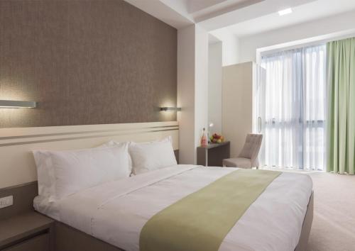 um quarto com uma cama grande e uma janela grande em Dave Hotel Yerevan em Yerevan