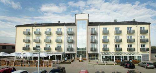 a large white building with cars parked in a parking lot at Stadthotel Donauwörth in Donauwörth