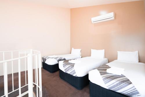 a row of three beds in a room at HarbourView Apartment Hotel (now Arrow on Spencer) in Melbourne
