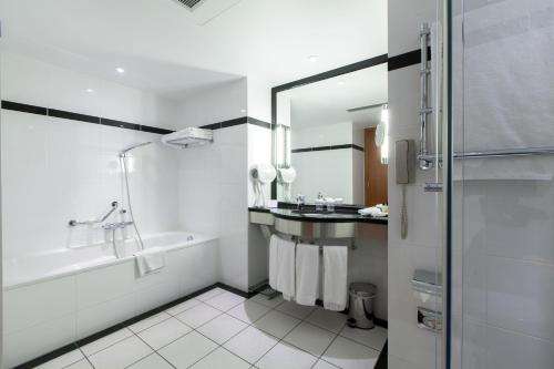 a white bathroom with a tub and a sink at Crowne Plaza Brussels Airport by IHG in Zaventem