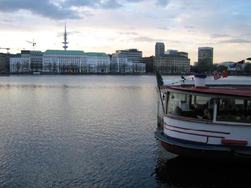 a boat in the water with a city in the background at Pension am Rathaus in Hamburg