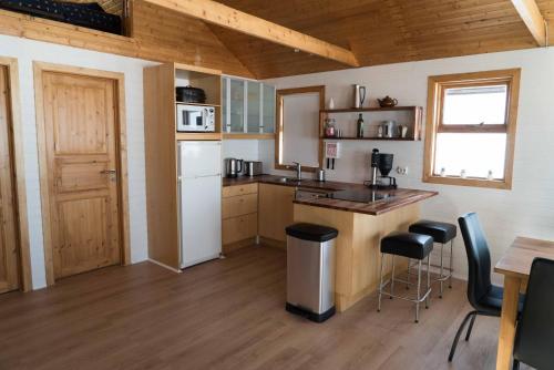 a kitchen with a sink and a counter with stools at Riverside Lodge with breathtaking view in Kirkjubæjarklaustur