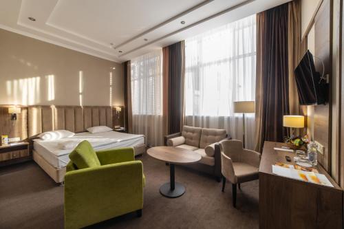 um quarto de hotel com uma cama, uma mesa e cadeiras em HELIOPARK Residence em Penza
