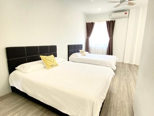 two beds in a room with white and yellow pillows at Grace Homestay Tawau in Tawau