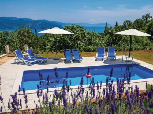 a swimming pool with blue chairs and umbrellas at Apartment Rea with Pool in Brseč