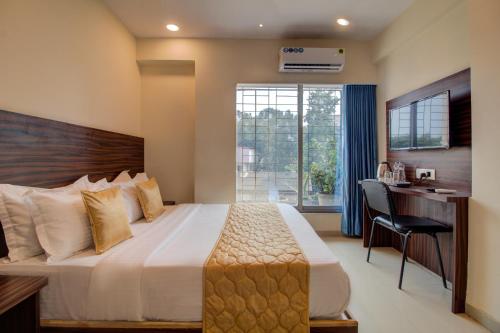 孟买Hotel Malad Inn opposite Malad Railway Station的一间卧室配有一张床、一张书桌和一个窗户。