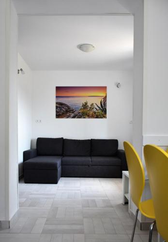 a living room with a black couch and yellow chairs at Apartment Meryl in Mravince