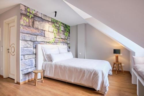 a bedroom with a white bed and a brick wall at The Kepos Hotel Erlangen in Erlangen