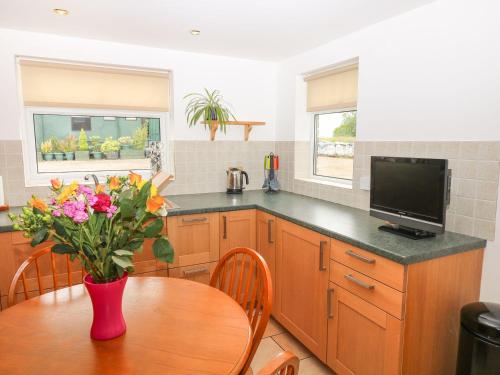 a kitchen with a table with a vase of flowers at The Cottage, Poplars Farm in Ashbourne