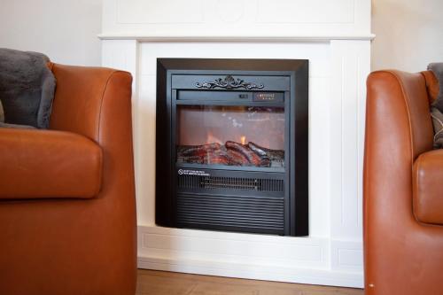 a fireplace in a living room with two chairs at Ferienwohnung Marinas Alpenblick in Inzell