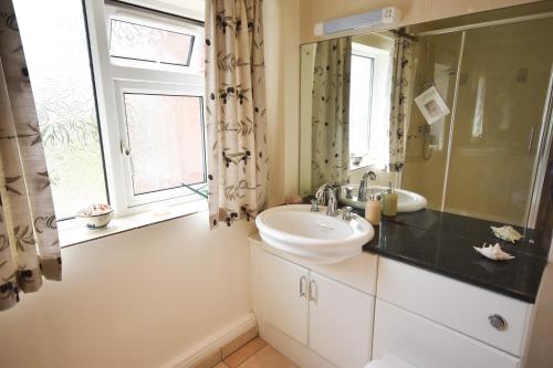 a bathroom with a sink and a mirror and a window at The Cottage, Poplars Farm in Ashbourne