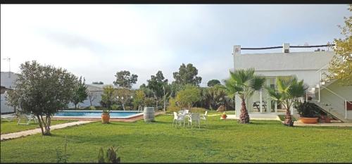 a yard with two white chairs and a pool at Joju in Sanlúcar la Mayor