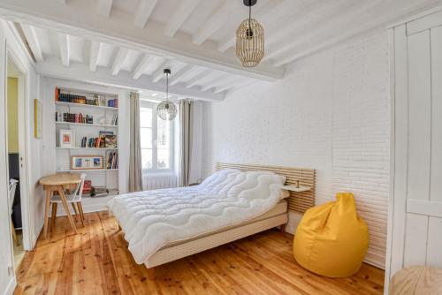 a white bedroom with a large bed and a wooden floor at Sea You Soon in Langrune-sur-Mer