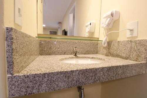 a bathroom counter with a sink and a phone at Acqua Inn Maceió Ponta Verde in Maceió