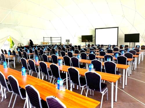 a large room with tables and chairs and a screen at 4 Żywioły Falenty Ośrodek Konferencyjno-Szkoleniowy in Raszyn