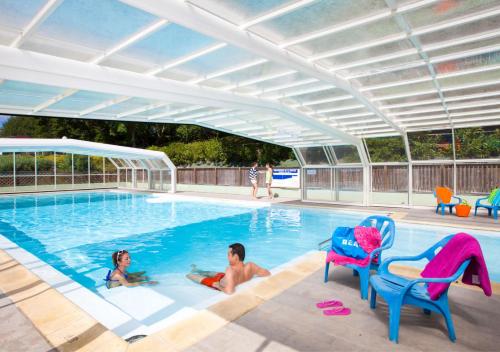 2 enfants jouant dans une piscine sous un parasol dans l'établissement Camping Le Paradis, à Talmont-Saint-Hilaire