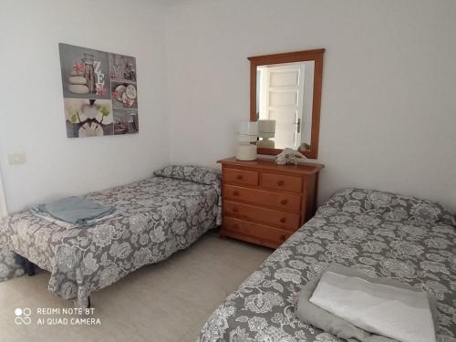 a bedroom with two beds and a dresser and a mirror at Villa in Parque Santiago 1 , sea View and all the Confort That you Need! in Playa de las Americas