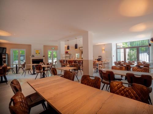 a dining room with wooden tables and chairs at Hôtel & SPA Ventoux Provence "Domaine des Tilleuls" in Malaucène