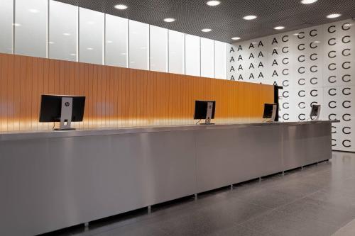 a baggage claim area in an airport with two monitors at AC Hotel Barcelona Fórum by Marriott in Barcelona