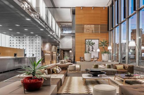 a lobby with couches and tables and plants at AC Hotel Barcelona Fórum by Marriott in Barcelona