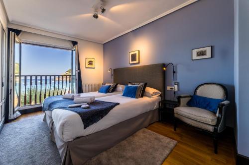 a bedroom with a bed and a chair and a window at LA CONCHA BEACHVIEW apartment in San Sebastián