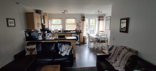 sala de estar con sofá y cocina en Ben Lomond Cottage, en Arrochar