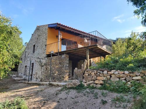 uma antiga casa de pedra com um deque no topo em Quinta do Rio em Vale do Serrão
