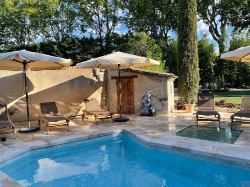 - une piscine avec des chaises et des parasols à côté dans l'établissement Mas Gabriel - St Rémy de Provence, à Saint-Rémy-de-Provence