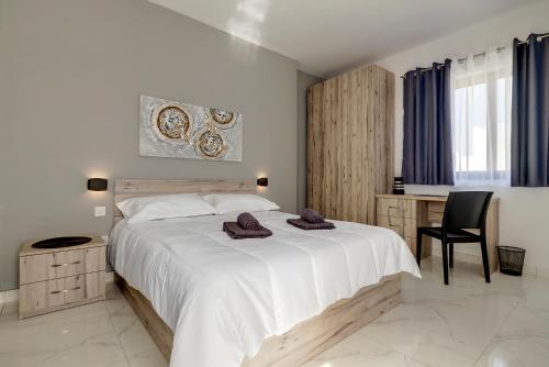 1 dormitorio con 1 cama blanca grande y toallas. en Chic 2BR Penthouse steps from the Promenade, en Sliema