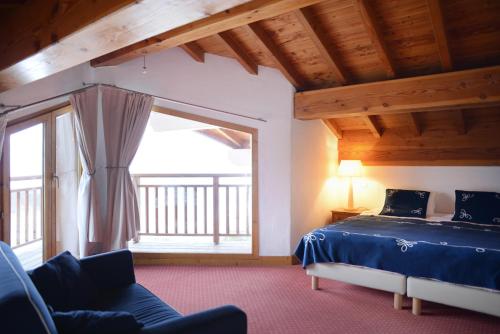 a bedroom with a bed and a large window at Goélia Les Chalets des Deux Domaines in Peisey-Nancroix