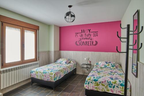 1 dormitorio con 2 camas y pared de color rosa en CASA RURAL ENTREVIÑAS, en San Bernardo