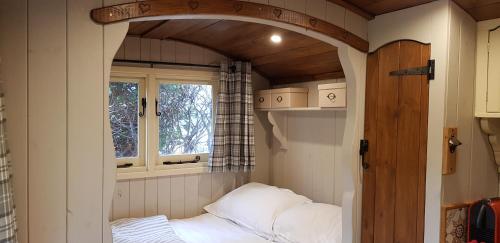 a small room with a bed and a window at Elmdale Hut - Shepherds Hut in Yatton
