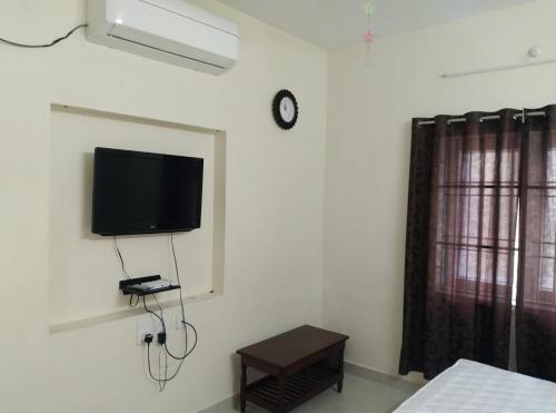 a bedroom with a tv on the wall and a table at Aarudhara Holiday Home (A Home away from Home) in Puducherry