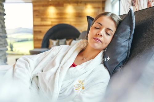 a woman laying on a couch wrapped in a towel at Landhotel Voss im TalVital in Saalhausen