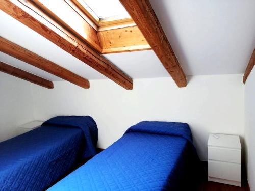 two beds in a room with wooden beams at Casa Leonilla in Pellizzano