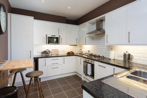 a kitchen with white cabinets and a sink at Priestley House City Centre-Free Parking in York