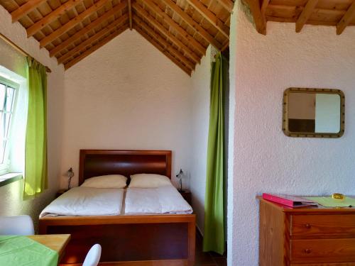 a bedroom with a bed with green curtains and a table at Vivenda Flores - Apartment Hibisco in Lomba