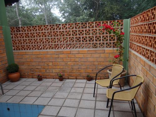 un patio con 2 sillas y una pared de ladrillo en Eco Pousada Sinimbu, en Cáceres