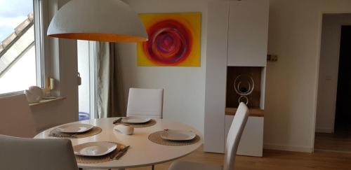 einen weißen Esstisch mit einem weißen Stuhl und einem Gemälde in der Unterkunft Drosselnest Moderne Design-Wohnung Hier ist alle neu! in Minden